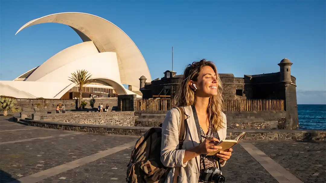 A woman enjoying an immersive audio experience in Santa Cruz de Tenerife, with the Auditorium and the Black Castle in the background.