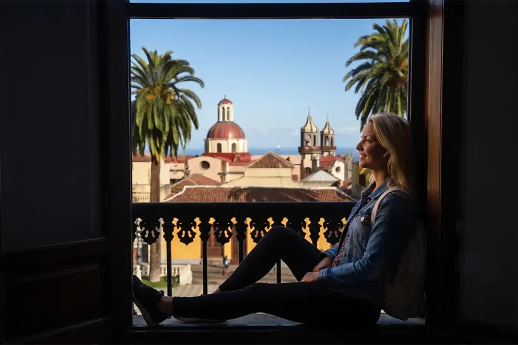 A traveller enjoying an immersive audio experience from a typical Canarian balcony overlooking the Church of La Concepción in La Orotava, Tenerife