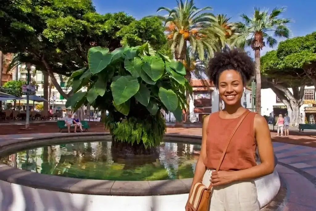 A young woman listening to an audio guide by the fountain in Plaza del Charco, Tenerife