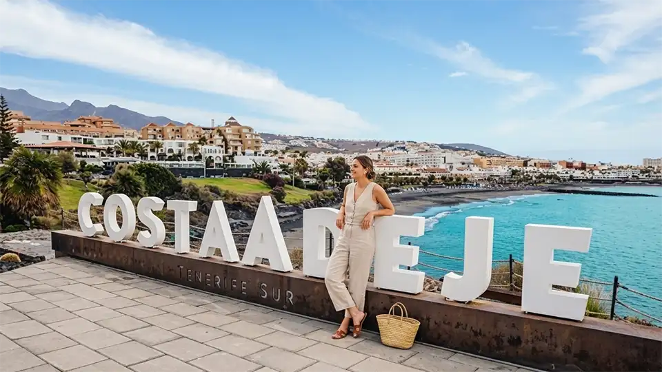 A traveller posing next to the sign for Costa Adeje, Tenerife