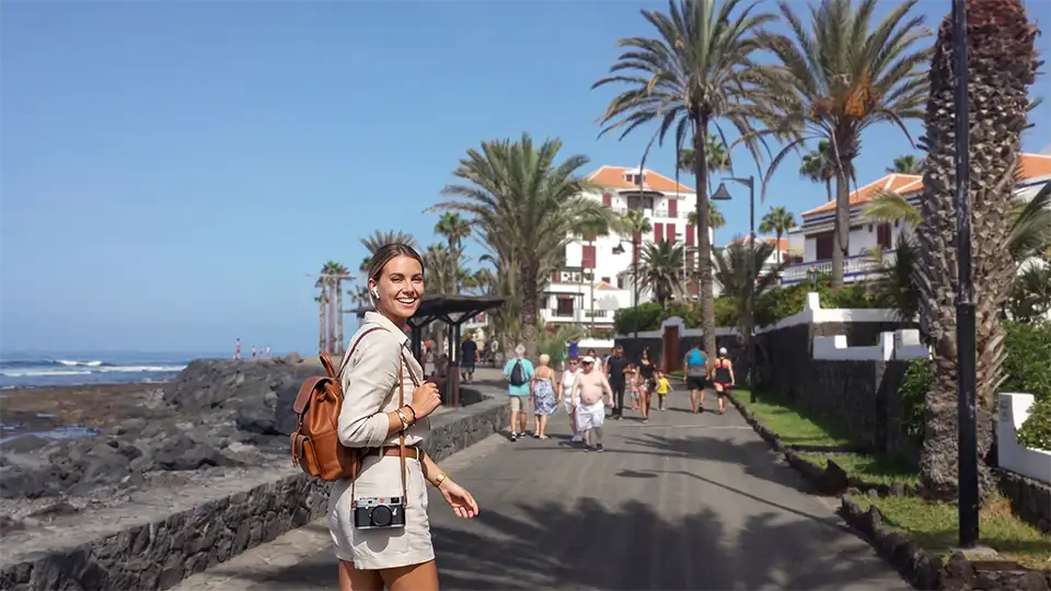 Eine Frau genießt ein immersives Audioerlebnis auf der Promenade Costa Adeje–Playa de las Américas, Teneriffa.