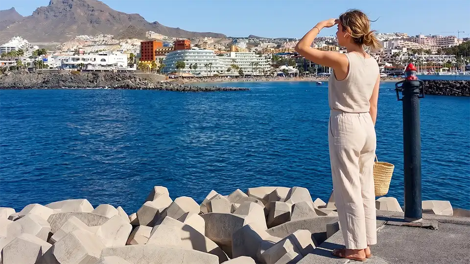 Une femme regarde la mer depuis la jetée de Puerto Colón, Costa Adeje, Ténérife