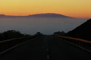 Vue en perspective au crépuscule sur une route de Ténérife, avec mer de nuages et La Gomera en arrière-plan
